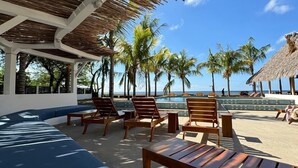 A beachside lounge with wooden furniture and a pool. - Hotel Kraken (Tola)