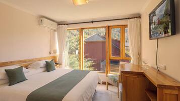 A hotel room with a bed, a desk, a chair, and a large window with curtains.