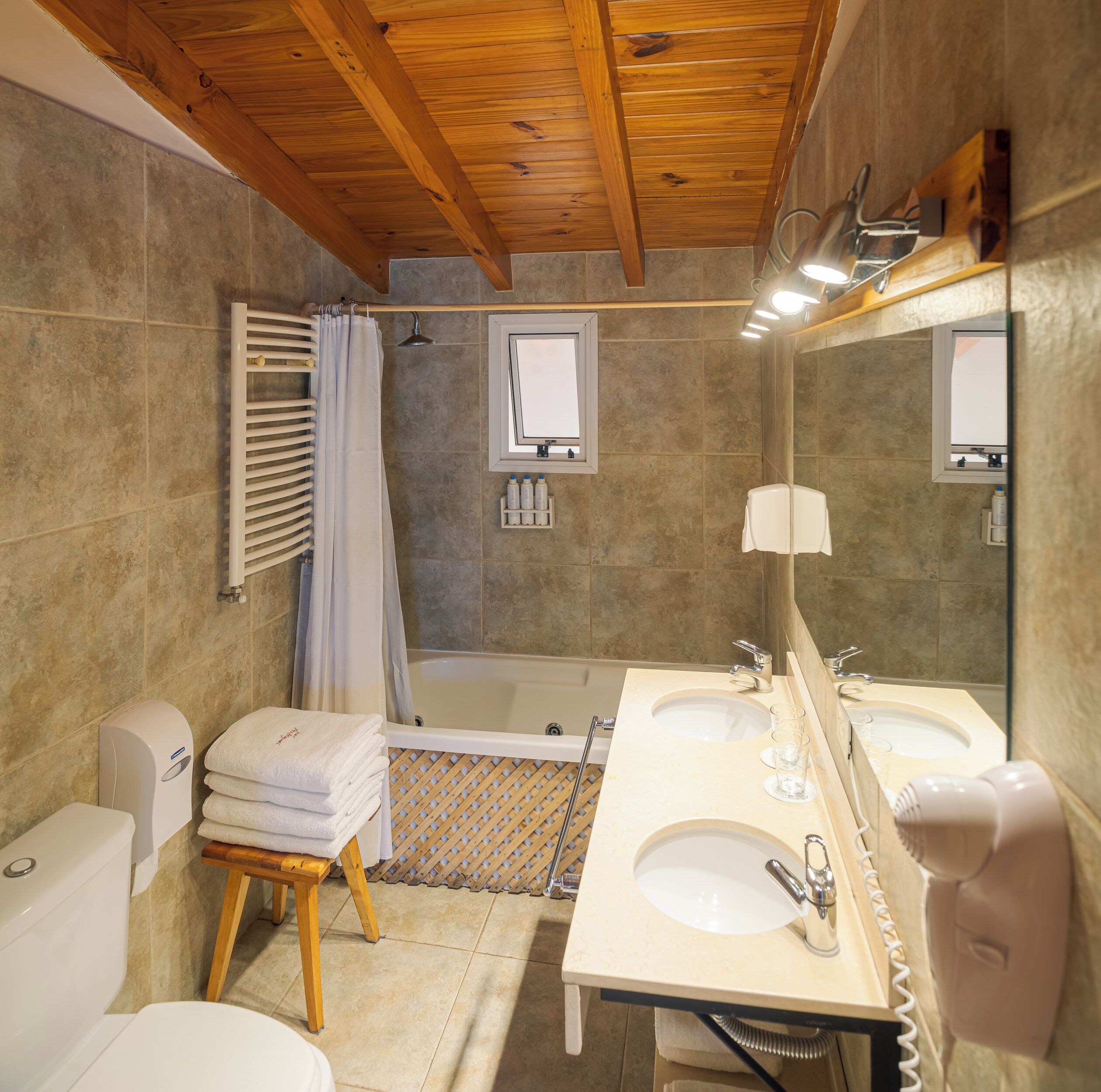 A bathroom with a wooden ceiling, two sinks, a bathtub, and a shower.