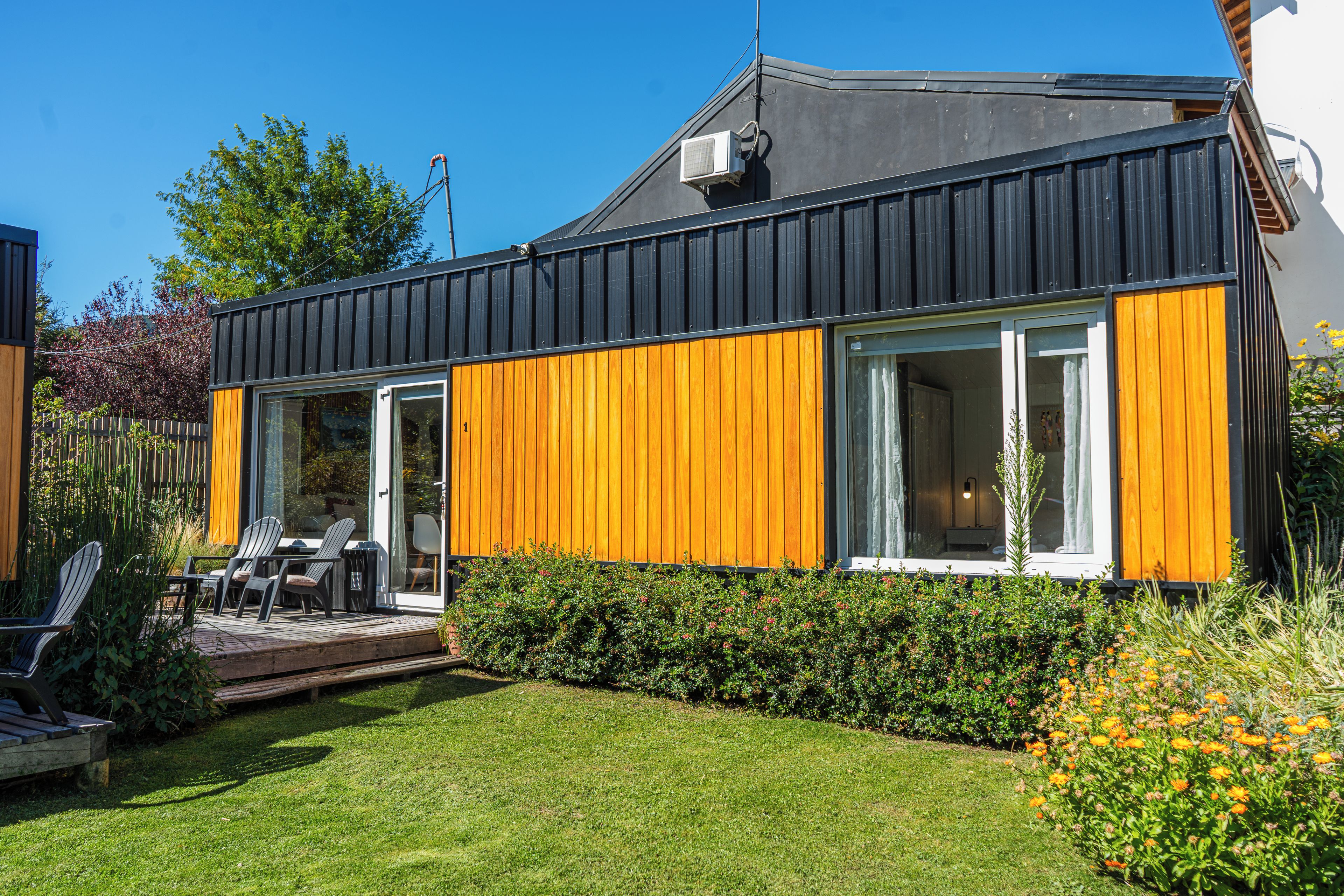 Une maison moderne dotée d’une terrasse, d’un espace salon extérieur et d’un jardin bien entretenu.