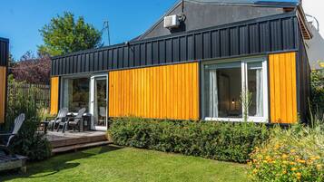 Une maison moderne dotée d’une terrasse, d’un espace salon extérieur et d’un jardin bien entretenu.