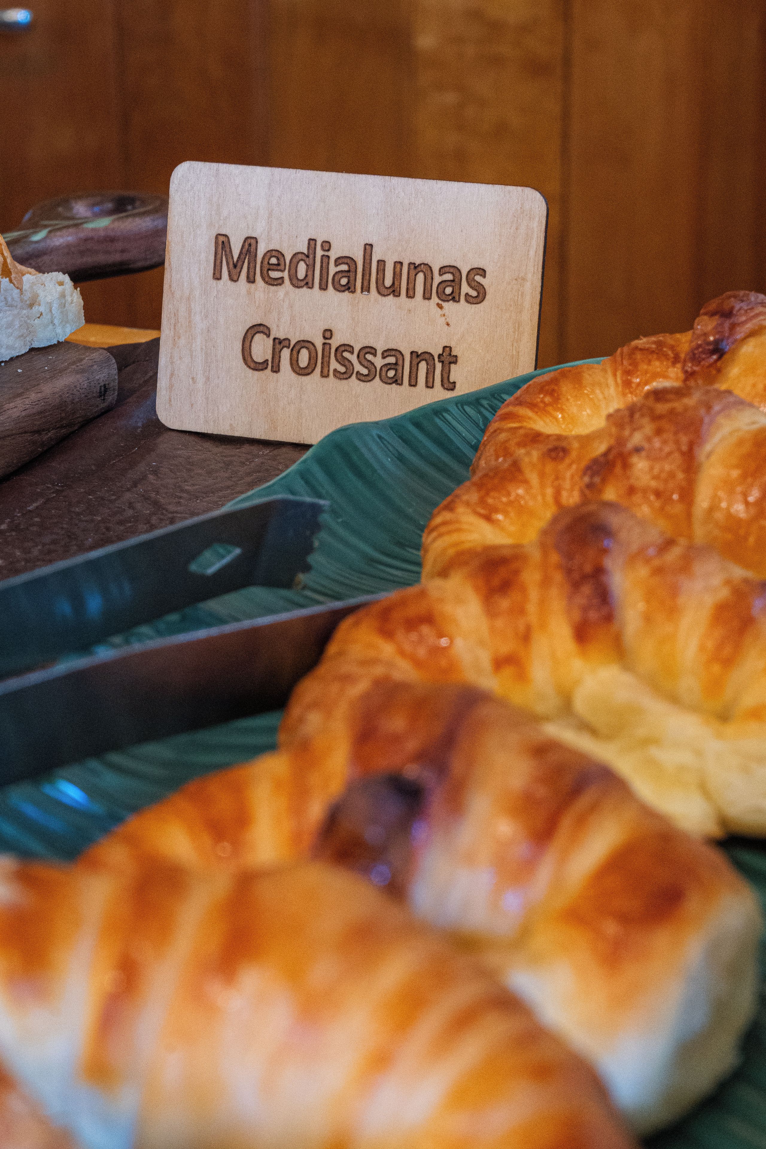 Una exhibición de pan, incluyendo medialunas y croissants, sobre una tabla de madera.