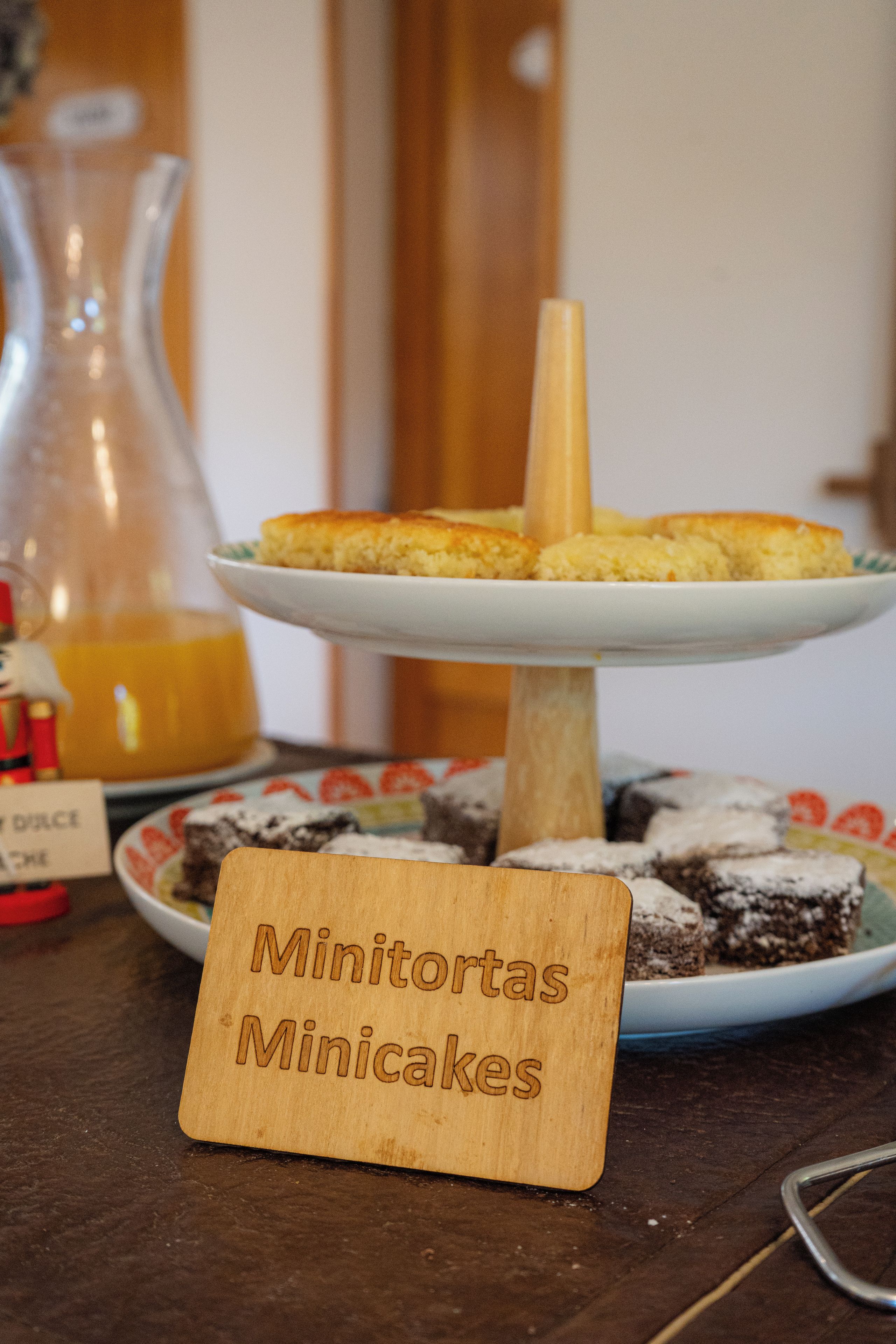 A wooden sign with the text 'Minitoritas Minicakes' in front of a dessert display.