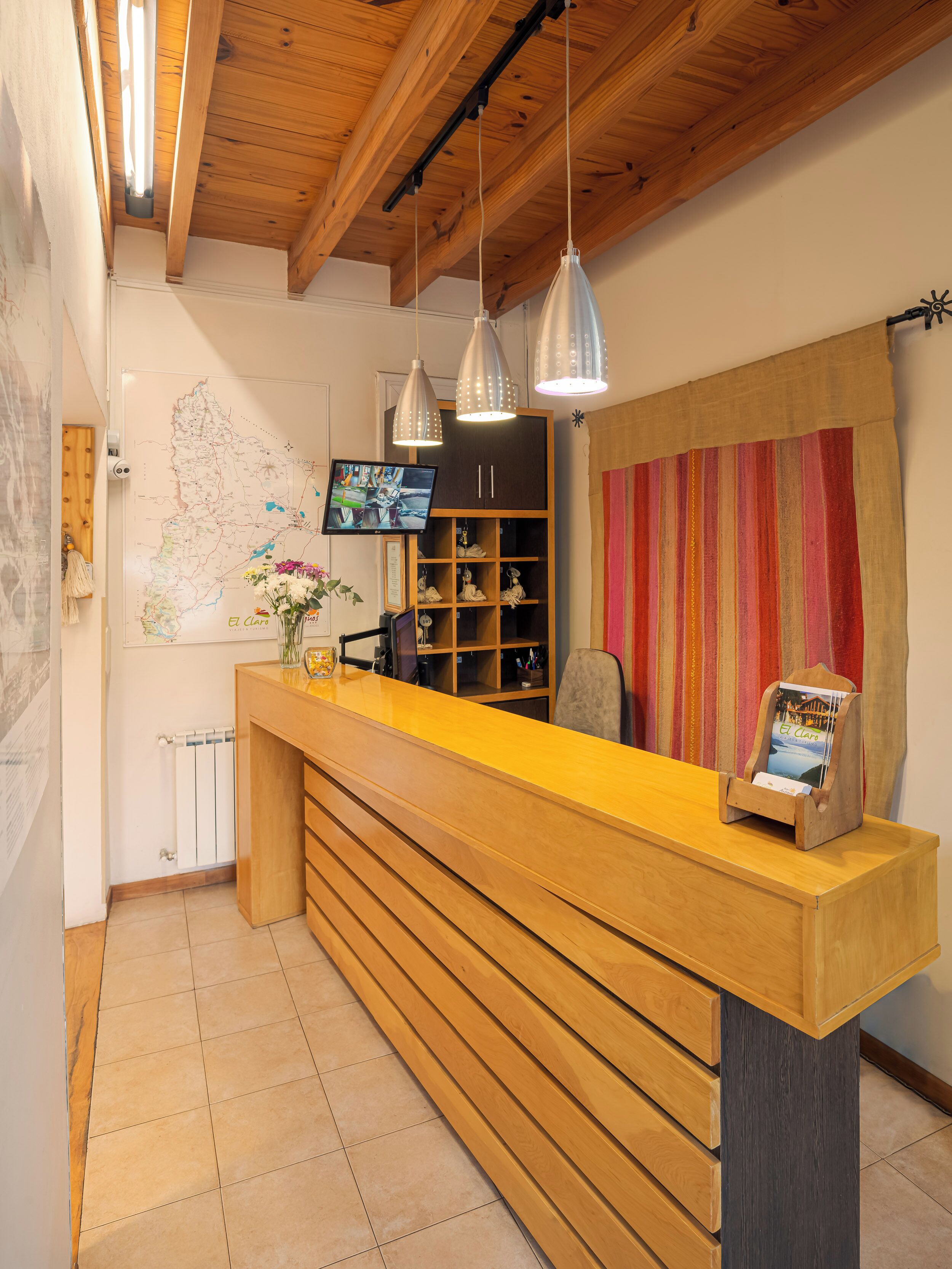 A reception desk with a wooden counter, a map on the wall, a television, and a shelf with decorative items.
