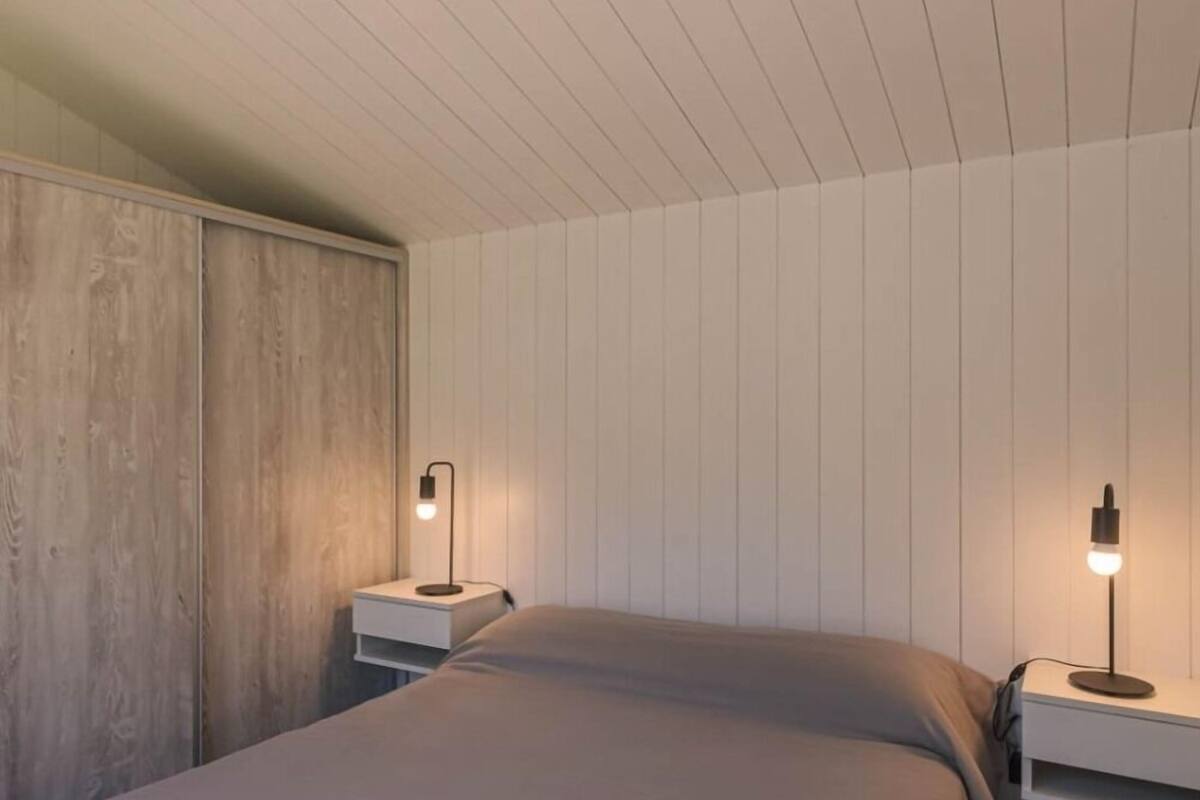 Une chambre à coucher avec un lit, deux tables de chevet et une armoire en bois.