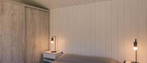 A bedroom with a bed, two bedside tables, and a wooden wardrobe.