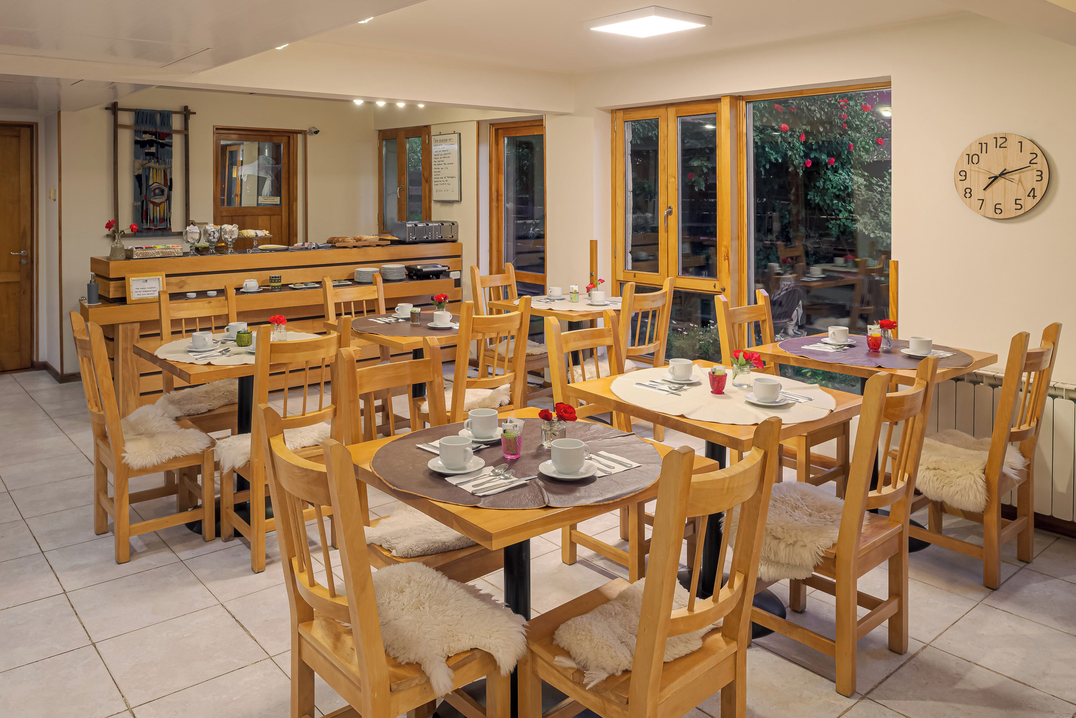 Un espace repas comprenant plusieurs tables et chaises en bois, ainsi que des services à thé et un buffet.