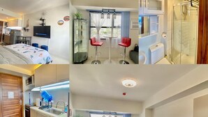 Una habitación de hotel moderna con cama, escritorio, baño con ducha y zona de cocina.