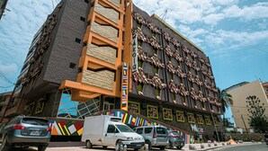 A multi-story building with a unique facade featuring geometric patterns and a mix of brick and stucco textures. - Wakola business hotels (Dakar)