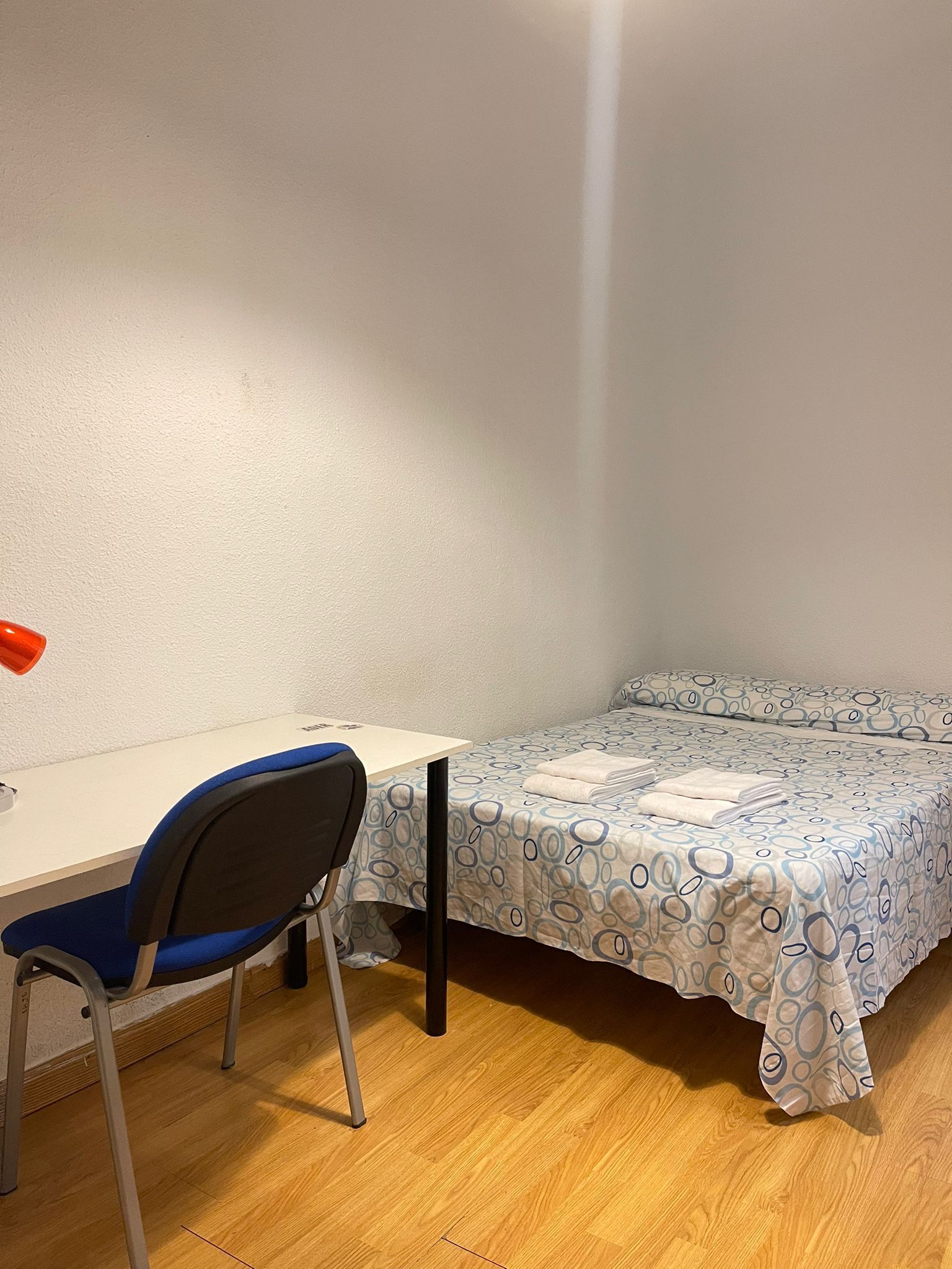 Una habitación pequeña con una cama individual, un escritorio y una silla.