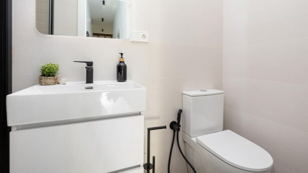 A modern bathroom with a white sink, black faucet, and a toilet. - ChezmoiHomes Santiago Duplex Penthouse (Granada)