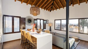 A spacious living area with a high ceiling, a central island with seating, and large windows offering city views. - ChezmoiHomes Santiago Duplex Penthouse (Granada)