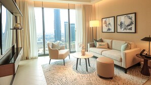 A modern hotel room with a large window offering a city view, a sofa, a coffee table, and a TV. - HiGuests - Address Opera Residences (Dubai)