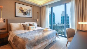 A modern hotel room with a large bed, a city view, and a desk with a lamp. - HiGuests - Address Opera Residences (Dubai)