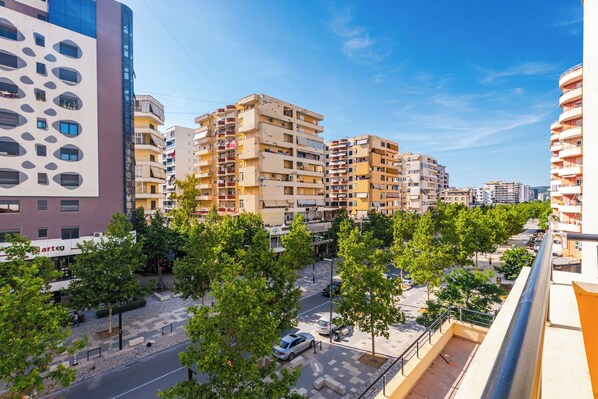 A multi-story residential building with balconies, a paved pedestrian area, and trees. - Kondo Stays - City Center Apartments (Vlorë)