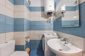 A bathroom with a toilet, sink, and mirror. - Kondo Stays - City Center Apartments (Vlorë)
