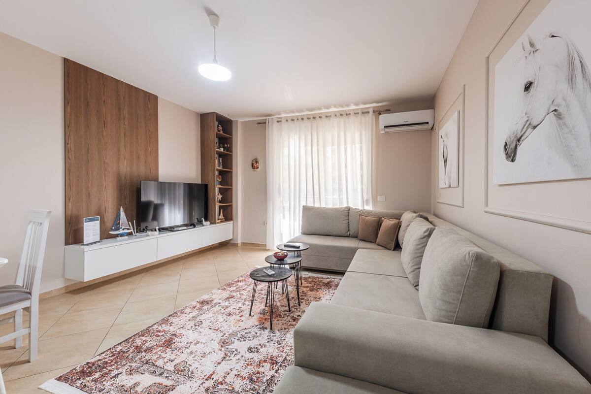 A modern living room with a sofa, a TV, a coffee table, and a patterned rug.
