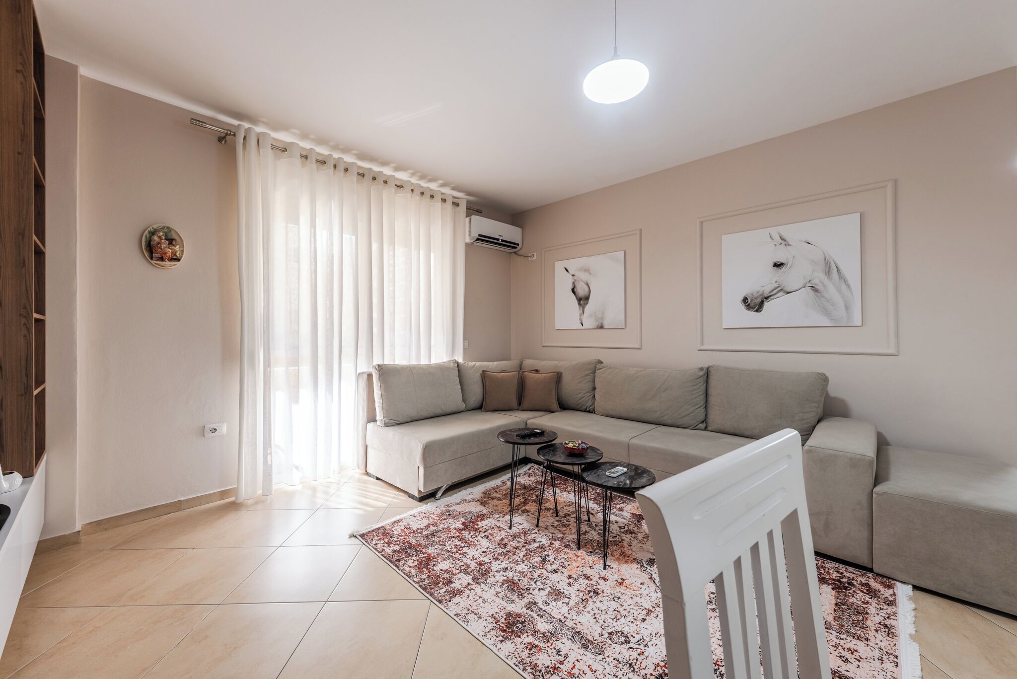 Un soggiorno moderno con un divano beige, un tavolino da caffè e due condizionatori fissati al muro.