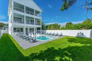 A two-story house with a swimming pool, multiple balconies, and a well-maintained lawn. - Seaspray: Pool! Sleeps 26! Beach access! (Destin)
