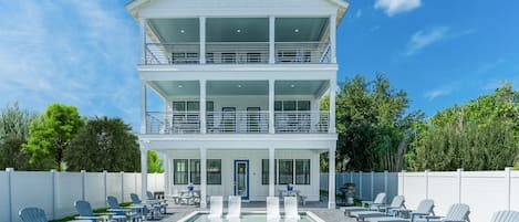 A two-story house with a pool and outdoor seating.