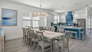 A spacious kitchen with a central island, white cabinetry, and a blue accent wall. - Seaspray: Pool! Sleeps 26! Beach access! (Destin)