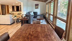 A spacious living area with a wooden ceiling, a large dining table, and a cozy seating arrangement.