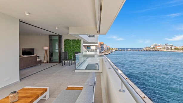 Ein moderner Balkon mit Blick auf das Meer und ein Kreuzfahrtschiff in der Ferne.