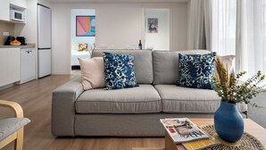 Un salon moderne avec un canapé gris, un vase bleu contenant des plantes et un magazine sur la table basse.