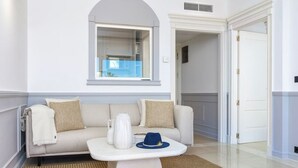 A modern living room with a beige sofa, a white coffee table, and a blue hat.