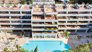 A multi-story hotel with balconies, a swimming pool, and outdoor seating areas.