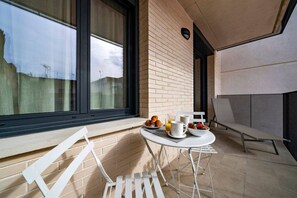 Een modern balkon met een ontbijtje, inclusief croissants, fruit en een kop koffie.