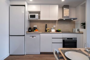 A compact kitchen with a refrigerator, microwave, coffee maker, and dishwasher.