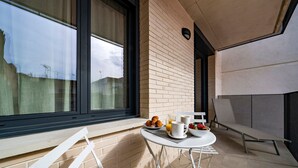 A modern balcony with a table set for breakfast, including croissants, fruit, and coffee. - Habitat Apartments Teatre 22 (Barcelona)