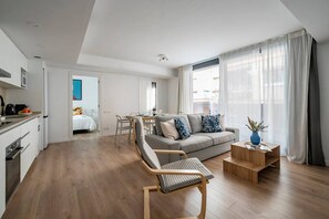 Un appartement moderne comprenant un coin repas, un canapé, une chaise en bois et une petite table sur laquelle est posé un vase.