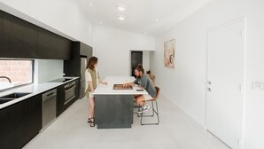 Une cuisine moderne avec des meubles de couleur sombre, un plan de travail blanc et un îlot central.