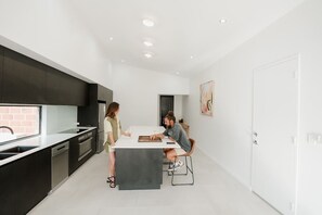 Een moderne keuken met donkere kastjes, een wit aanrechtblad en een centraal eiland.