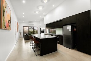 Une cuisine moderne dotée d’un îlot central, de meubles de rangement noirs et d’un grand réfrigérateur.