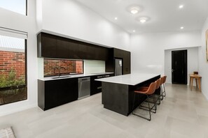 Eine moderne Küche mit einer großen Kochinsel, schwarzen Schränken und Blick auf eine Backsteinwand.
