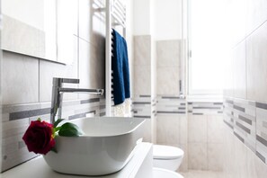 Un baño con un lavabo blanco, una toalla azul y un inodoro blanco.