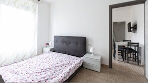 Un dormitorio con cama, mesita de noche y escritorio con silla.