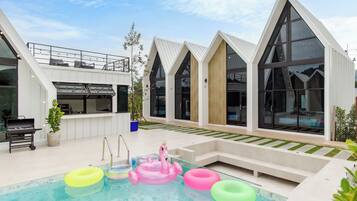 Un edificio moderno con piscina, zona de barbacoa y bañera de hidromasaje.