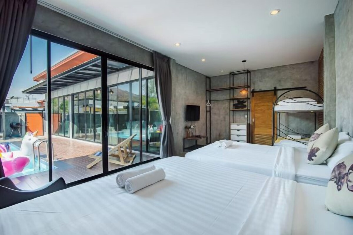 Una habitación de hotel moderna con dos camas, un amplio ventanal, vista a la piscina y un balcón.