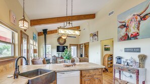 A kitchen with wooden cabinets, a built-in dishwasher, a coffee bar, and a large window. - Medicine Park Cottage: Walk to Lake Lawtonka! (Medicine Park)