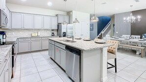 Una cocina moderna con una isla central, electrodomésticos de acero inoxidable e iluminación colgante.