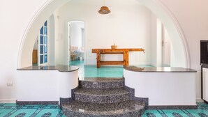 A modern interior with a staircase leading to a dining area, featuring a wooden table and chairs. - Villa Giusy 2 by BarbarHouse (Mancaversa)