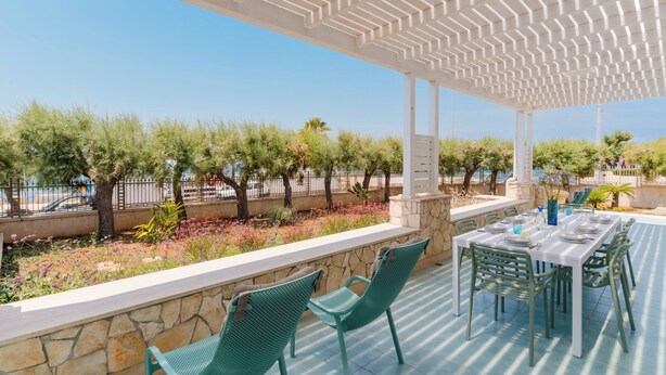 An outdoor patio with a white pergola, stone walls, and a view of trees and a fence. - Villa Giusy 2 by BarbarHouse (Mancaversa)