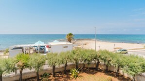 A coastal view with a beach, a parked car, and a building with a white roof. - Villa Giusy 2 by BarbarHouse (Mancaversa)