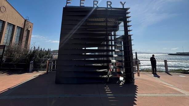 A modern building with the word "FERRY" on top, a clear sky, and a person standing by the waterfront. - Fabulous entire 2-bedroom house with onsite washer/dryer in Richmond near Bart. (Richmond)
