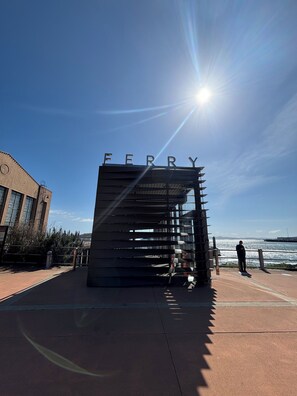 A modern building with the word "FERRY" on top, a clear sky, and a person standing by the waterfront. - Fabulous entire 2-bedroom house with onsite washer/dryer in Richmond near Bart. (Richmond)