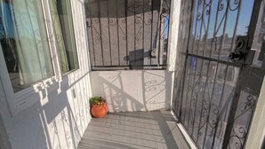 A covered outdoor area with a decorative metal gate, a potted plant, and a patterned floor design. - Fabulous entire 2-bedroom house with onsite washer/dryer in Richmond near Bart. (Richmond)